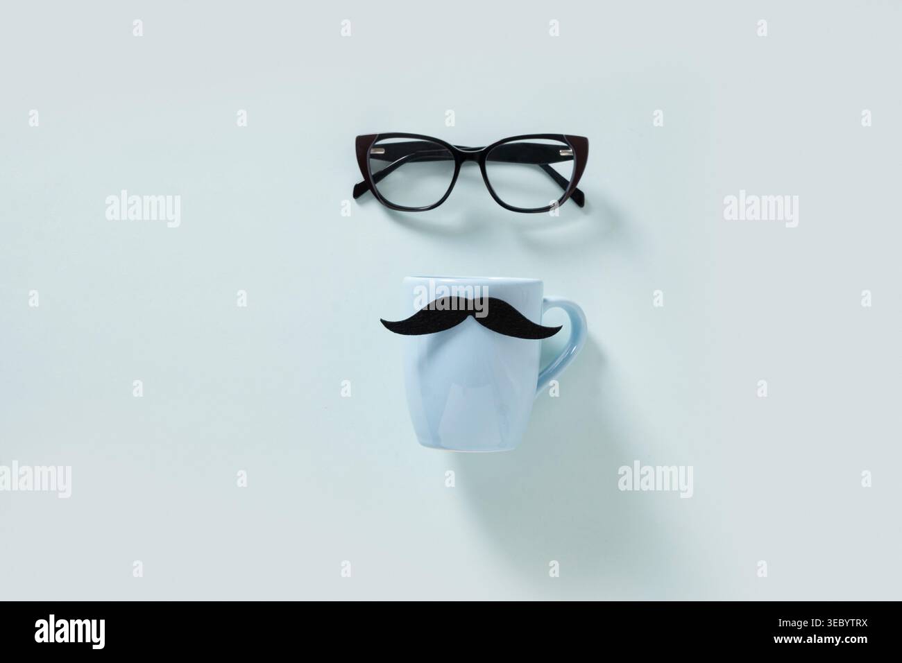 Eyeglasses and white mug with mustache arranged on light background, creative minimal composition, lifestyle concept, copy space, top view. Father day Stock Photo
