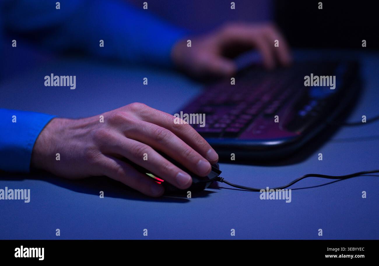 Person Using Computer Mouse and Keyboard in Dimly Lit Room During Evening Hours Stock Photo