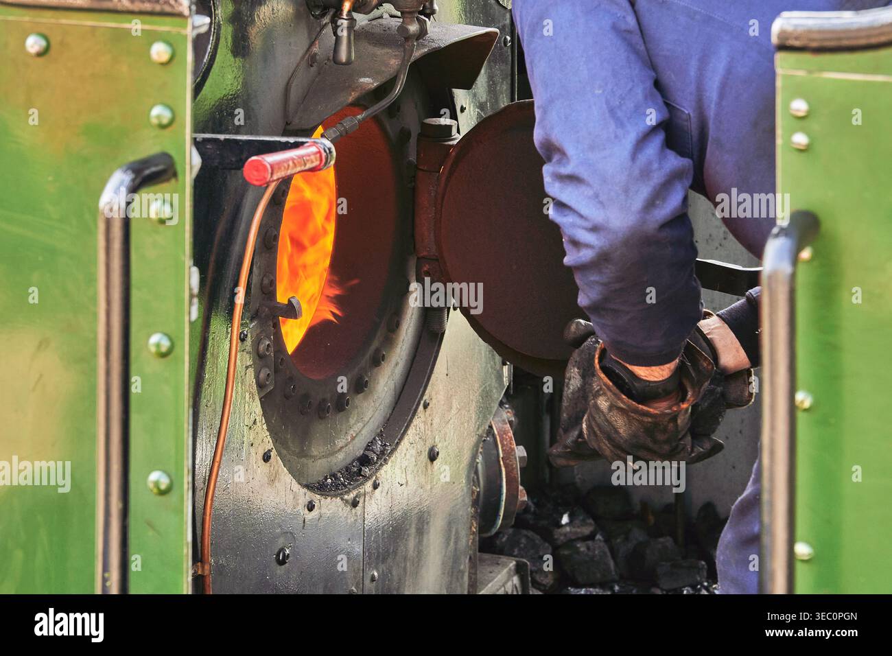 Steam locomotive firebox operation with worker feeding coal Stock Photo ...