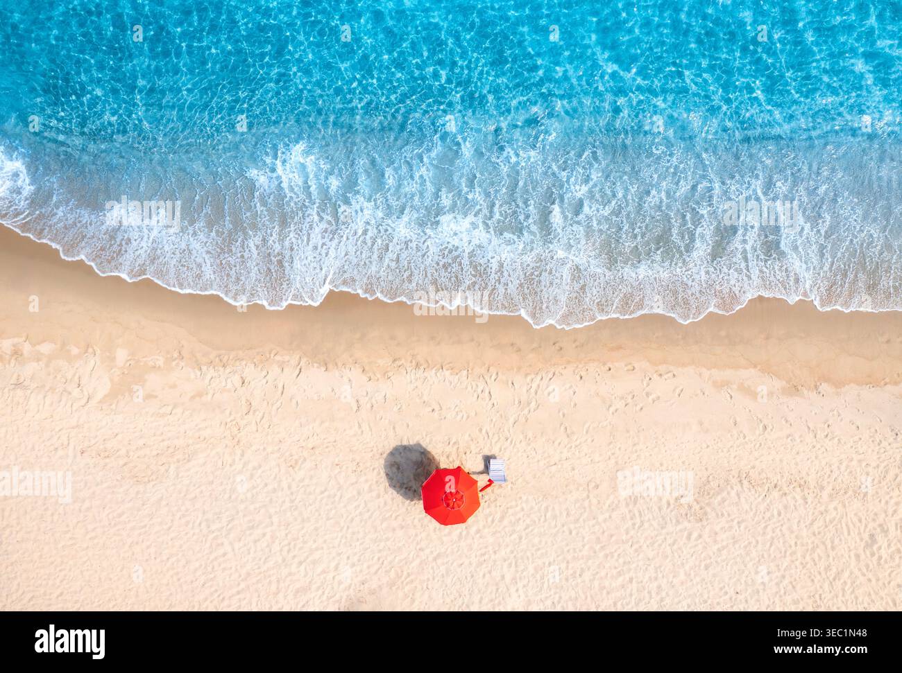 Aerial view of red umbrella on white empty sandy beach, blue sea Stock Photo