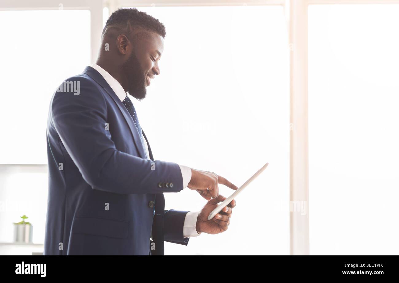 Young cheerful entrepreneur using digital tablet for business Stock Photo