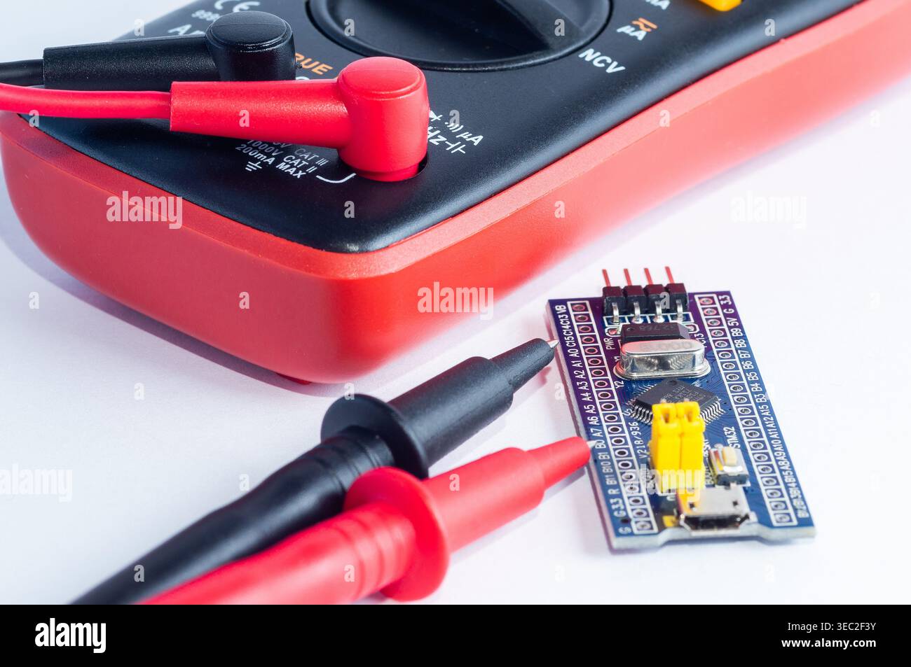 Multimeter with measurement probes and electronics board on a white background Stock Photo