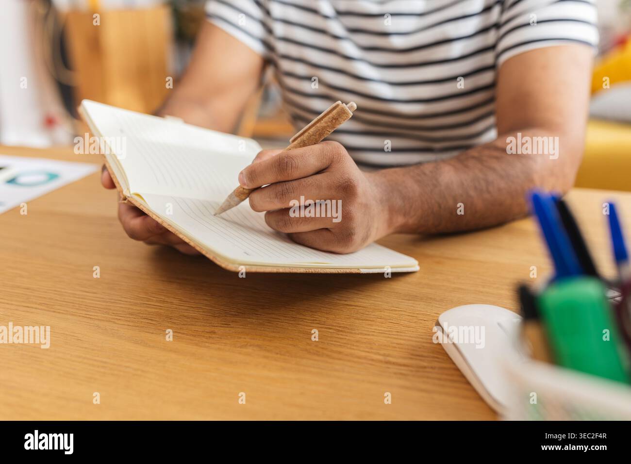 Young Indian man writing academic notes at desk Stock Photo