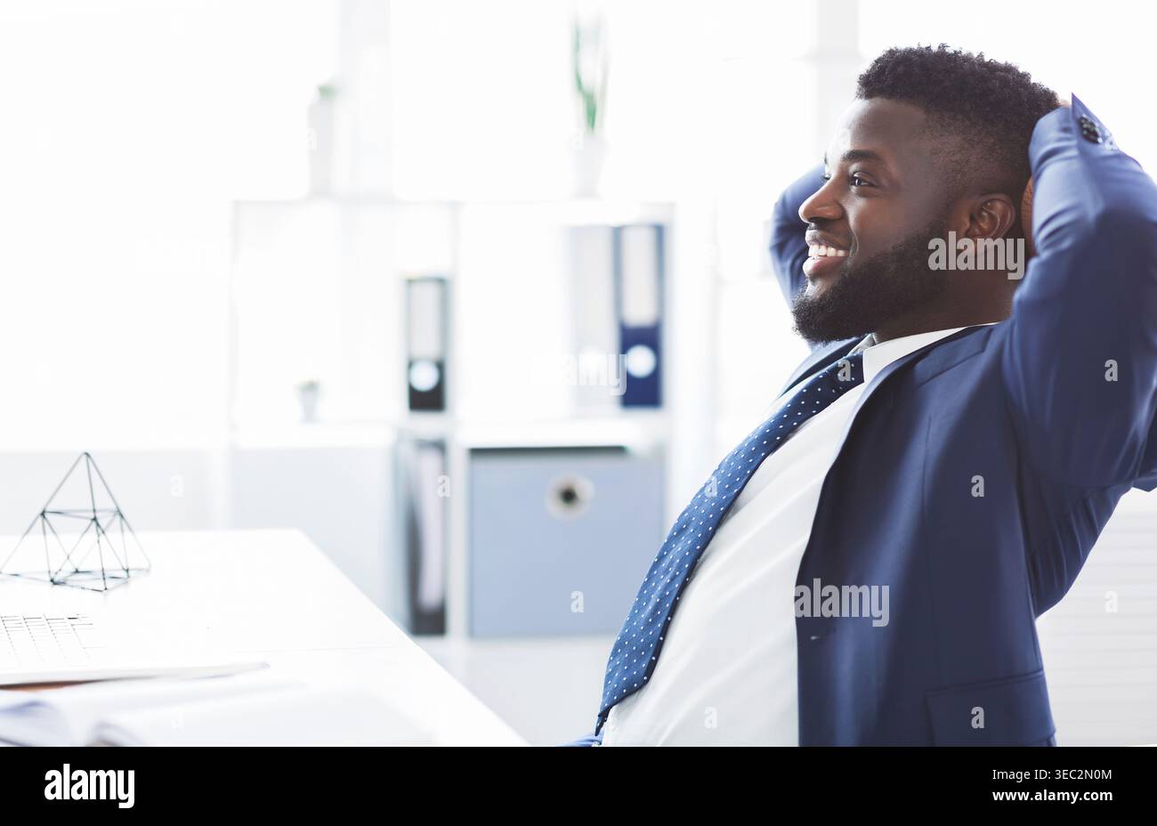 Dreamy african businessman leaning back in modern office Stock Photo