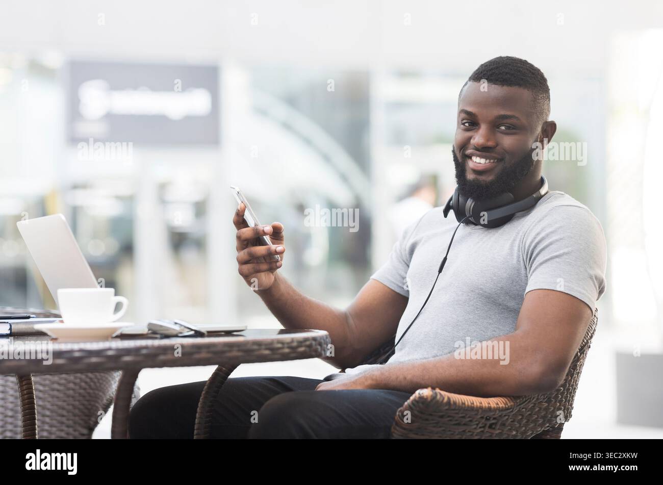 Young Man Enjoying Coffee While Using Smartphone at Outdoor Cafe Stock Photo