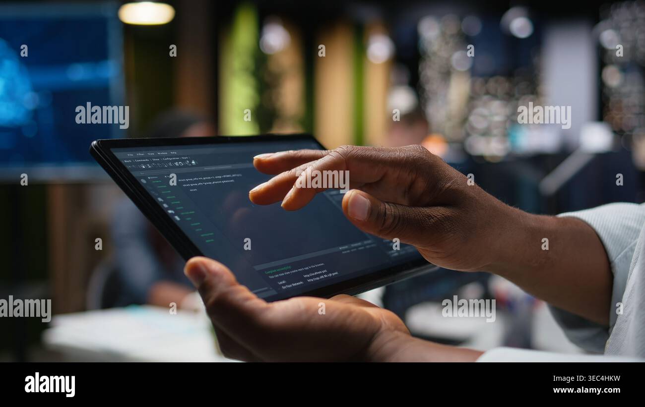 Close up of programmer typing code on touchscreen device, developing machine learning models to automate tasks in workspace. Developer checking app programming language scripts on tablet Stock Photo