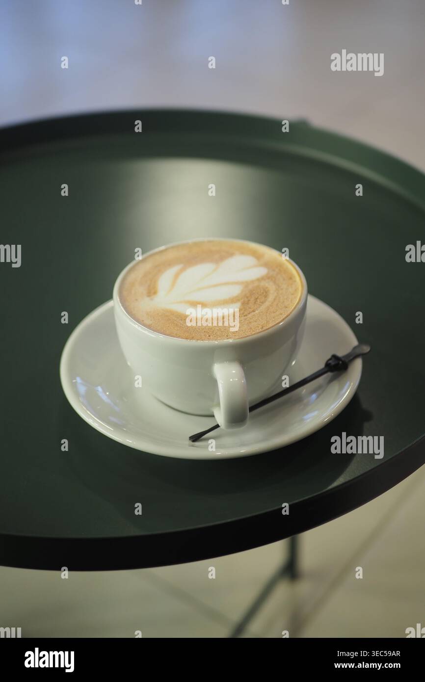 Coffee cup on a green tray in a cafe setting Stock Photo