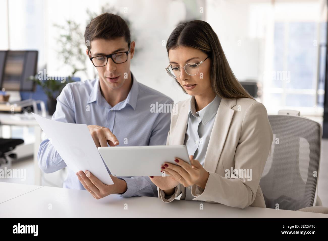Team collaborating on project details using tablet and printed documents Stock Photo