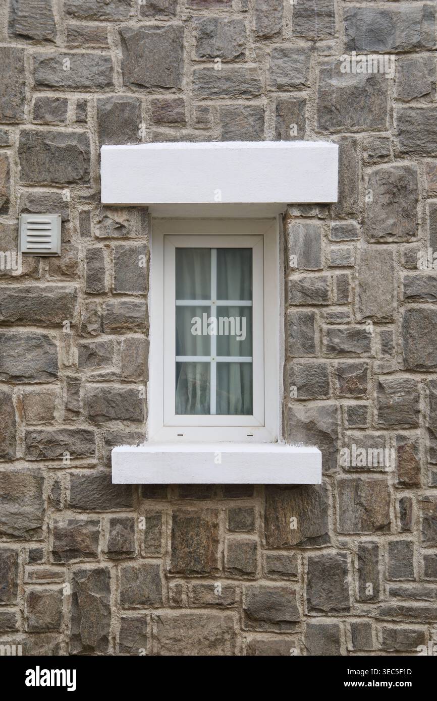 white framed window with internal muntins in stone wall, rectangular window with curtains and sill, front view full frame texture Stock Photo