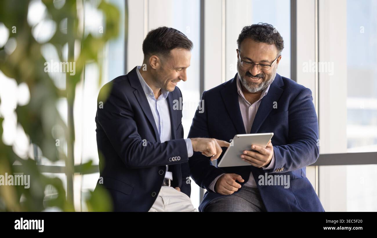 Two smiling businessmen reviewing information on digital tablet Stock Photo