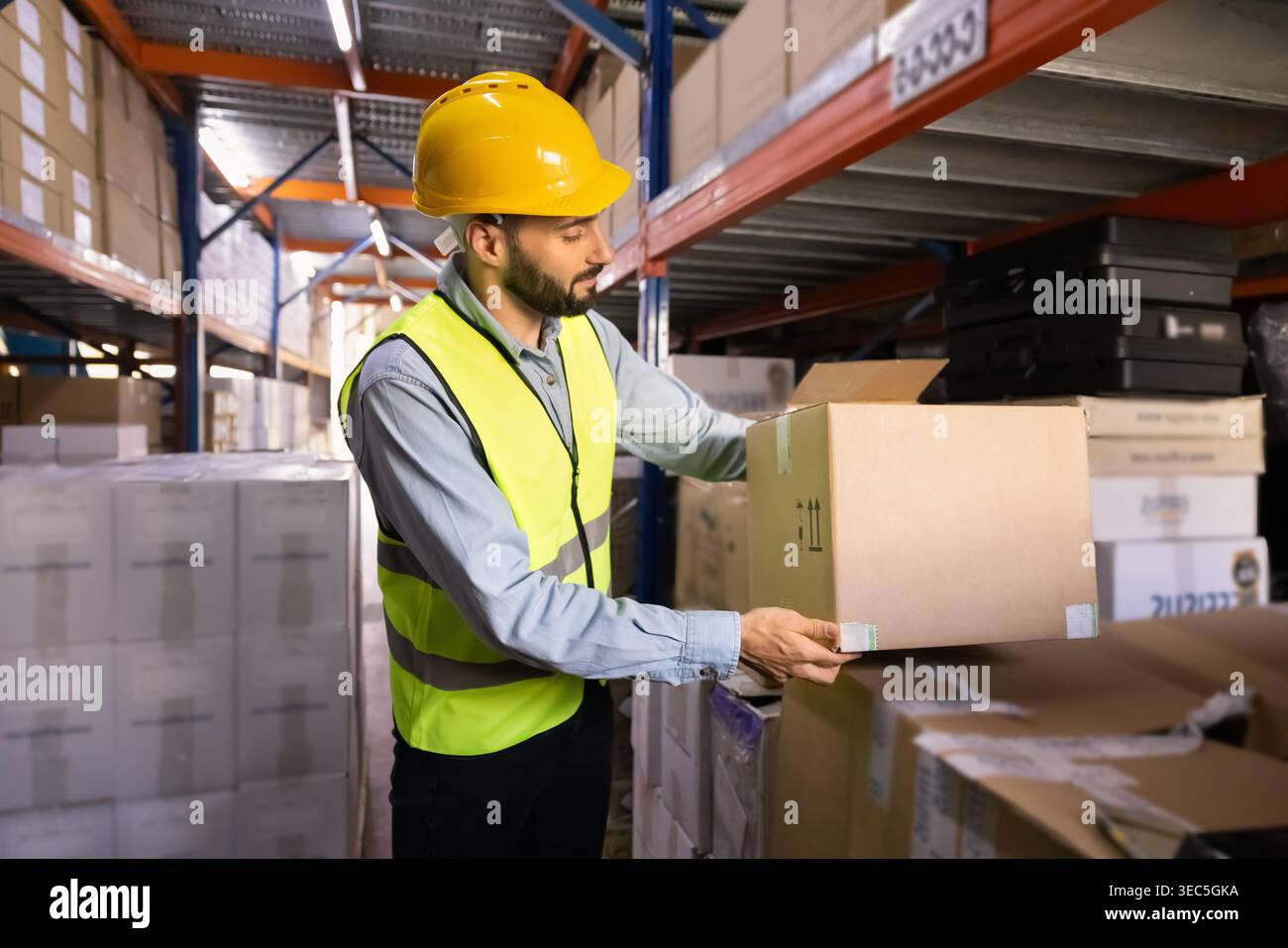 Worker in uniform organizing boxes on shelves in warehouse Stock Photo