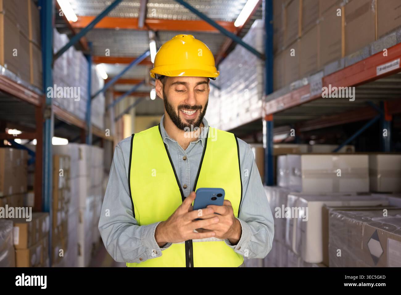 Warehouse worker using smartphone in logistics facility Stock Photo