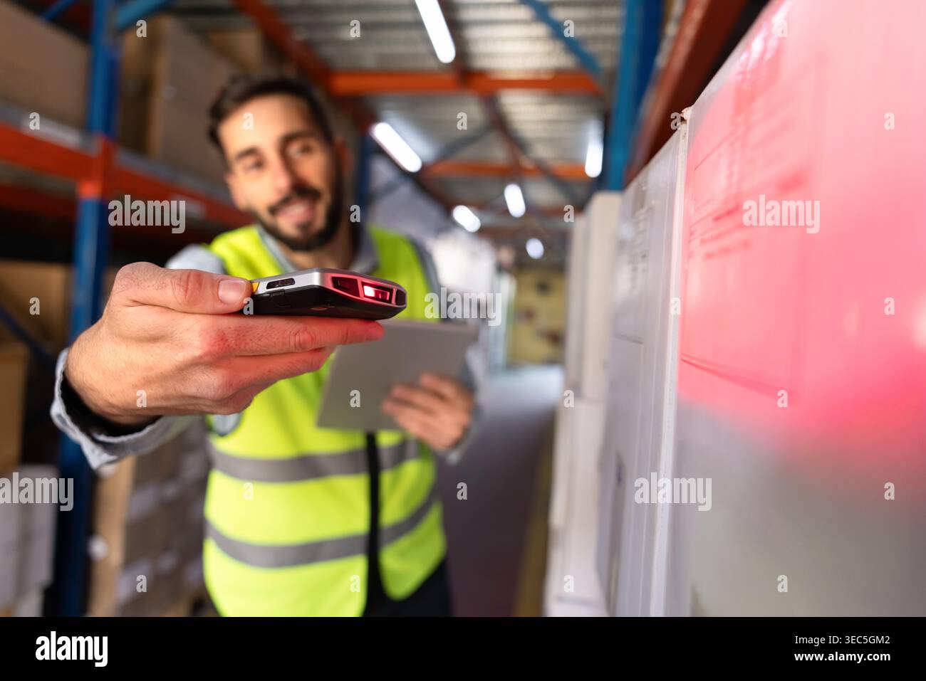 Worker scanning barcode on package with scanner in warehouse aisle Stock Photo