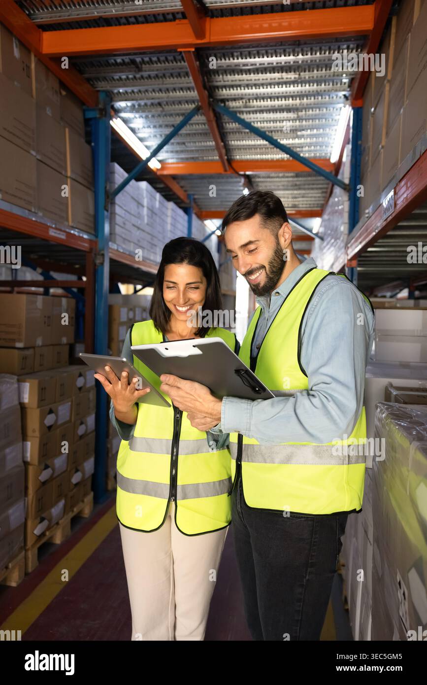 Warehouse workers reviewing inventory data on digital tablet and clipboard Stock Photo