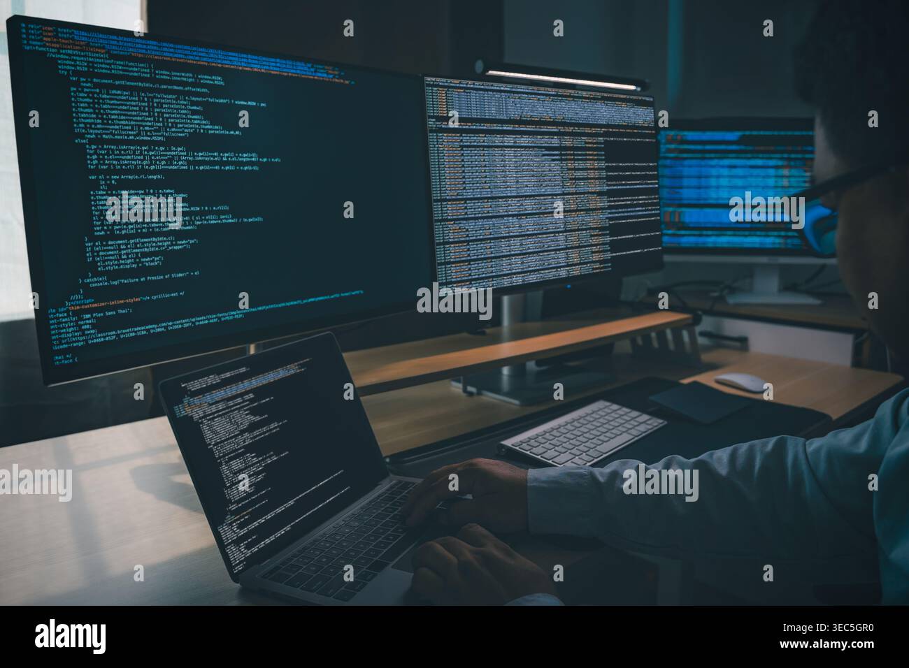 Developing programmer Website design at a multi monitor workstation with laptop and screens displaying scripts, showing web development, coding, softw Stock Photo