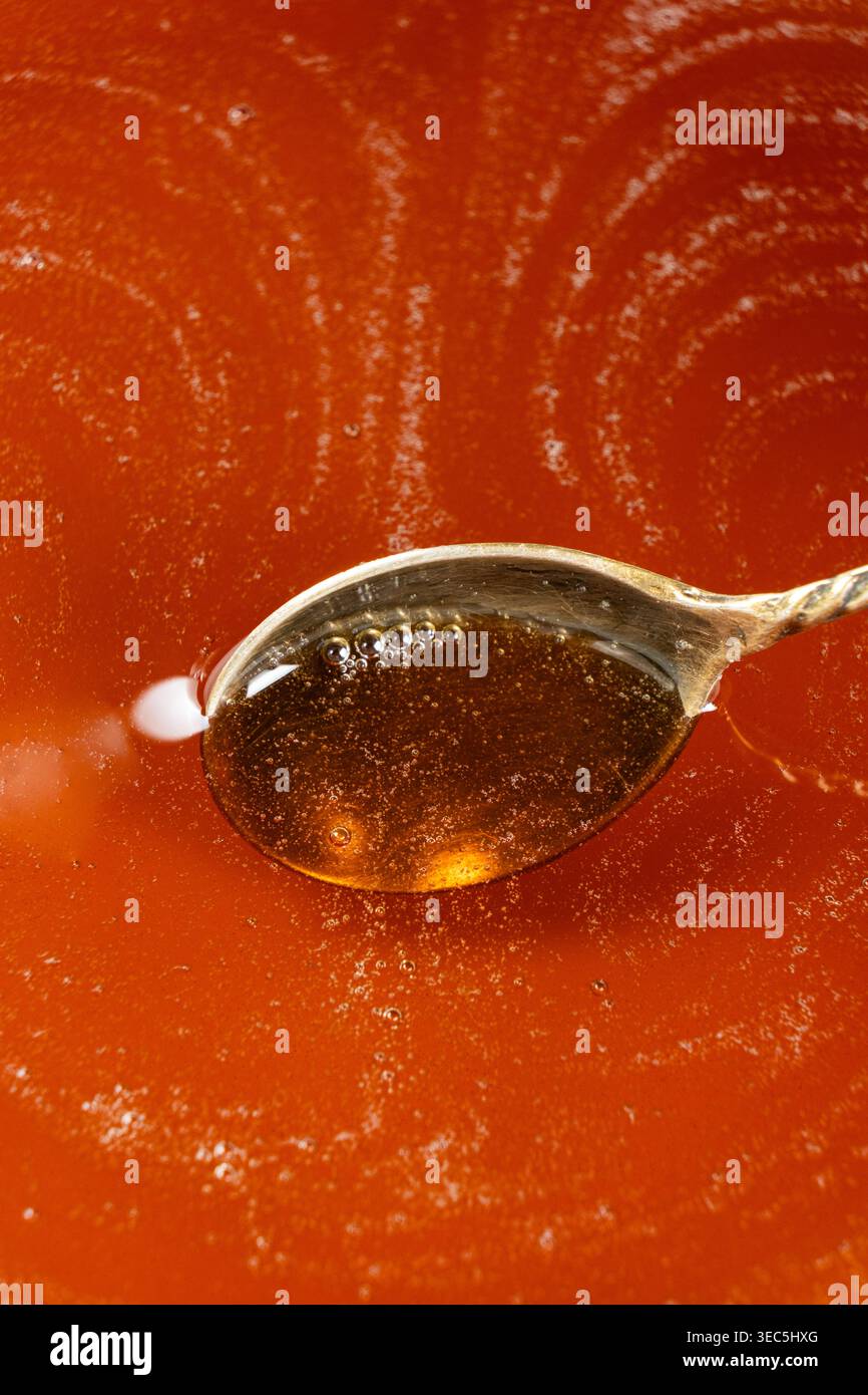 Spoon filled with golden maple syrup. Stock Photo