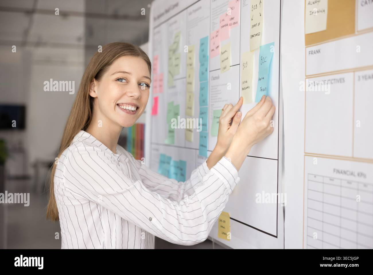 Female project manager placing or adjusting sticky notes Stock Photo