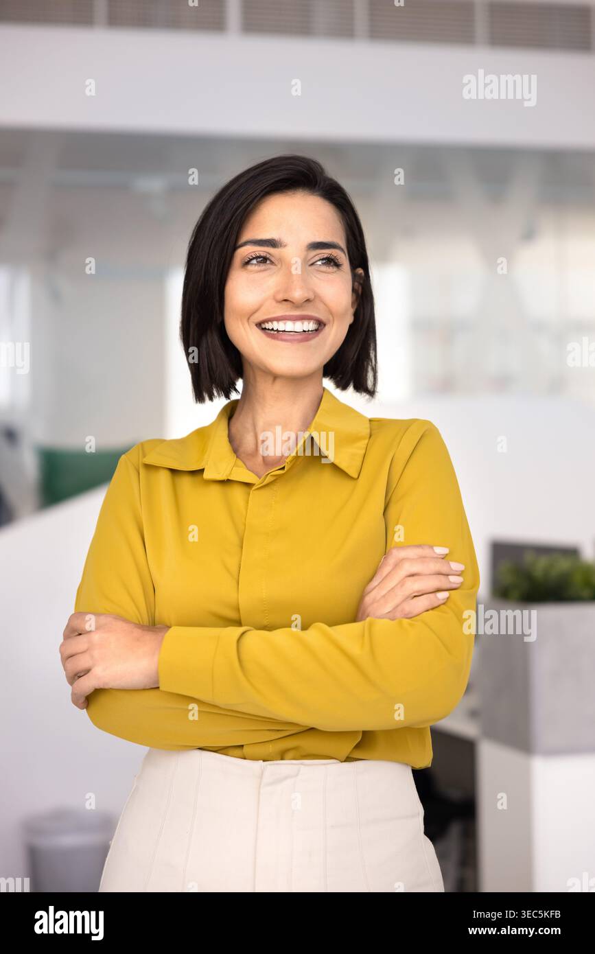 Confident businesswoman standing in office with arms crossed Stock Photo