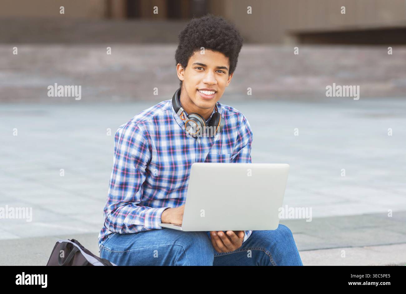 Young Student Working on Laptop Outdoors in Urban Setting During Sunny Day Stock Photo