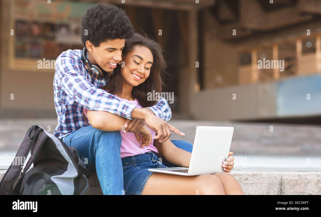 Young Couple Enjoying a Casual Moment Together While Working on a Laptop Outside Stock Photo