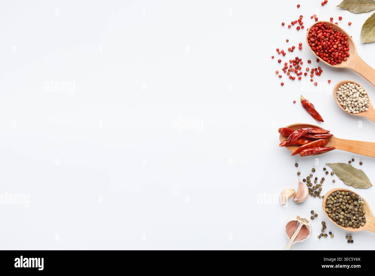 Various peppercorns in spoons on white background Stock Photo