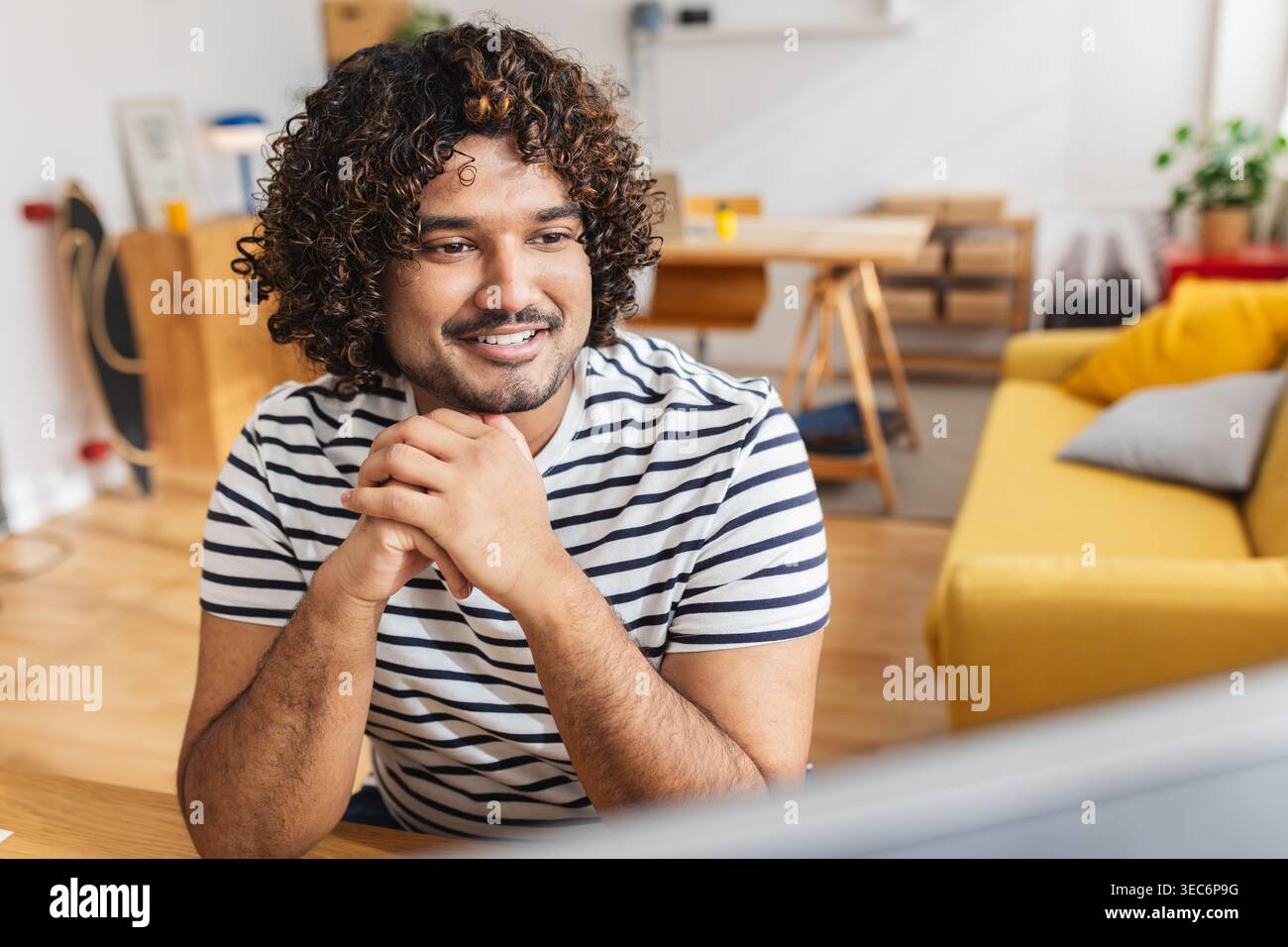 Young Indian man smiling while attending online class Stock Photo