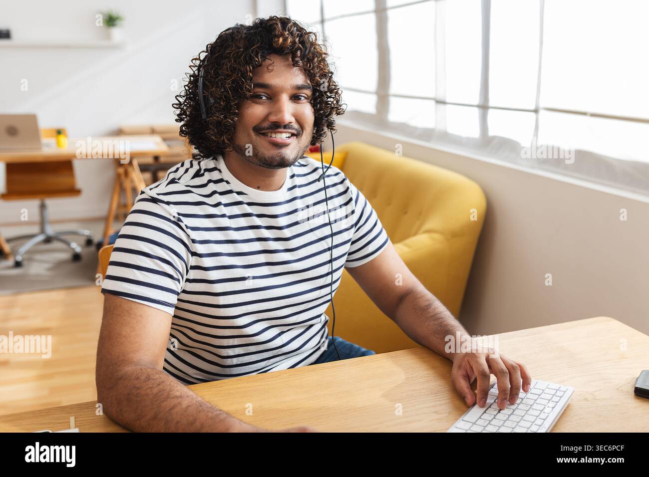 Young Indian man using computer with headset Stock Photo