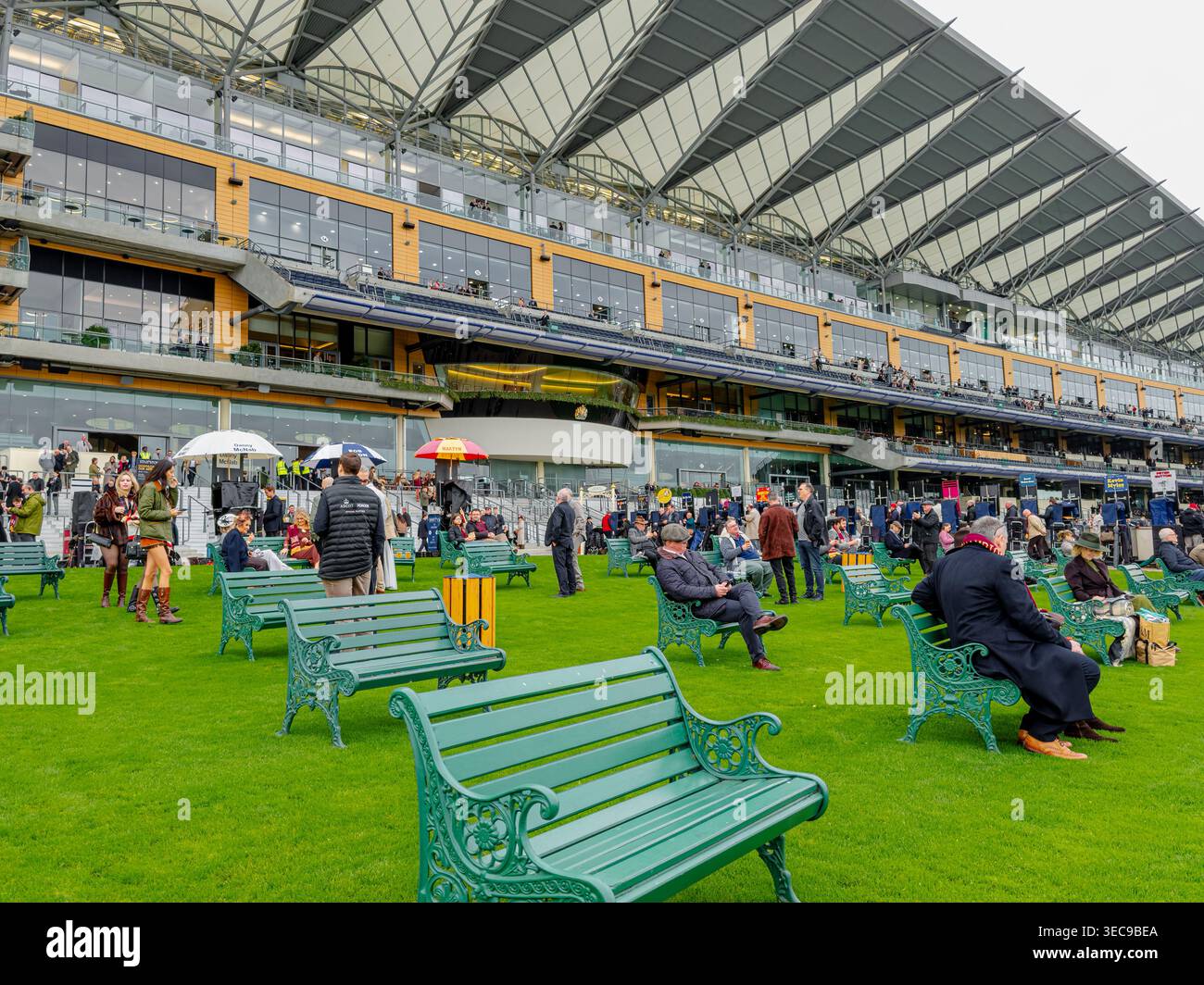 People sitting on green benches in front of the grandstand at Ascot ...