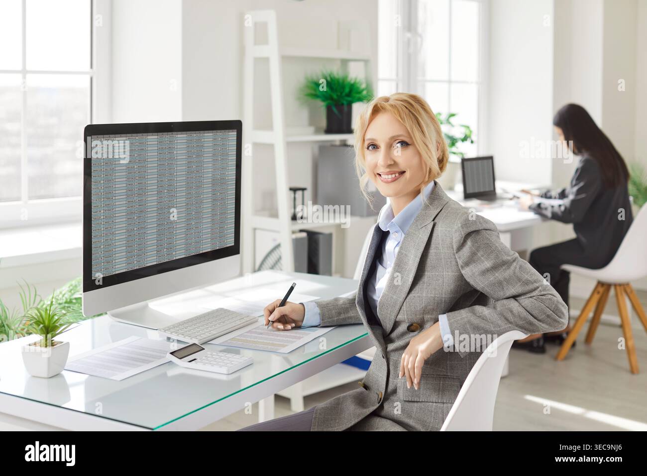 Confident businesswoman sitting at desk, working with financial data and analyzing spreadsheet. Stock Photo