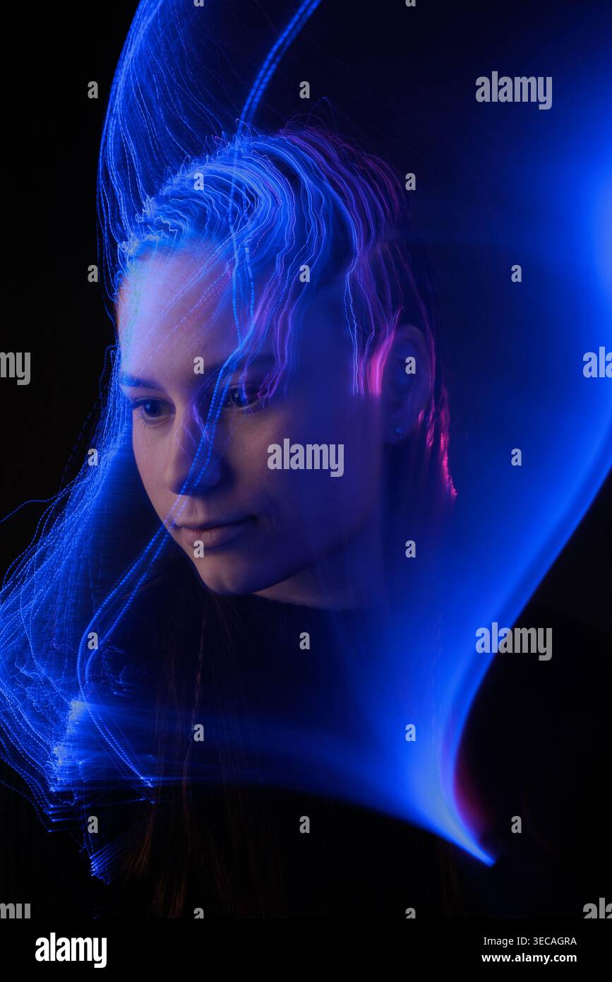 Woman portrait with blue light trails visualizing artificial intelligence, cognition, and neural processing for technology concepts. Stock Photo