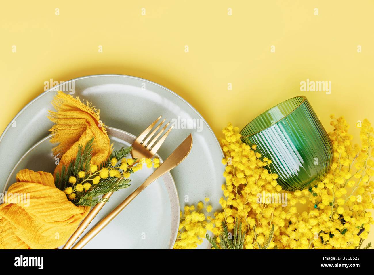Festive spring composition with mimosa and elegant tableware Stock Photo