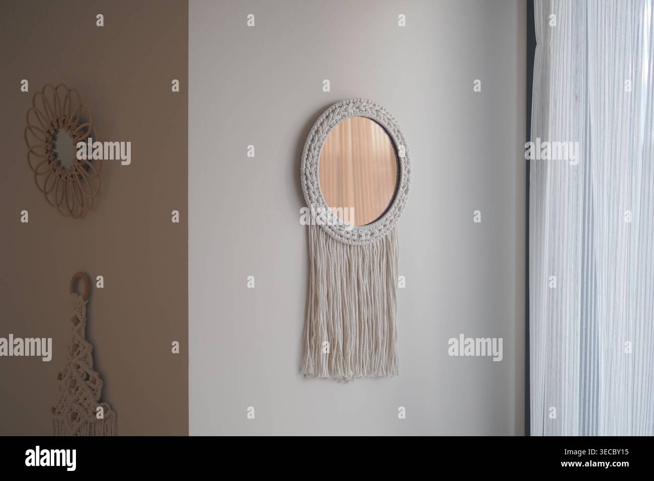 Decorative mirror hangs on wall with fringe design Stock Photo