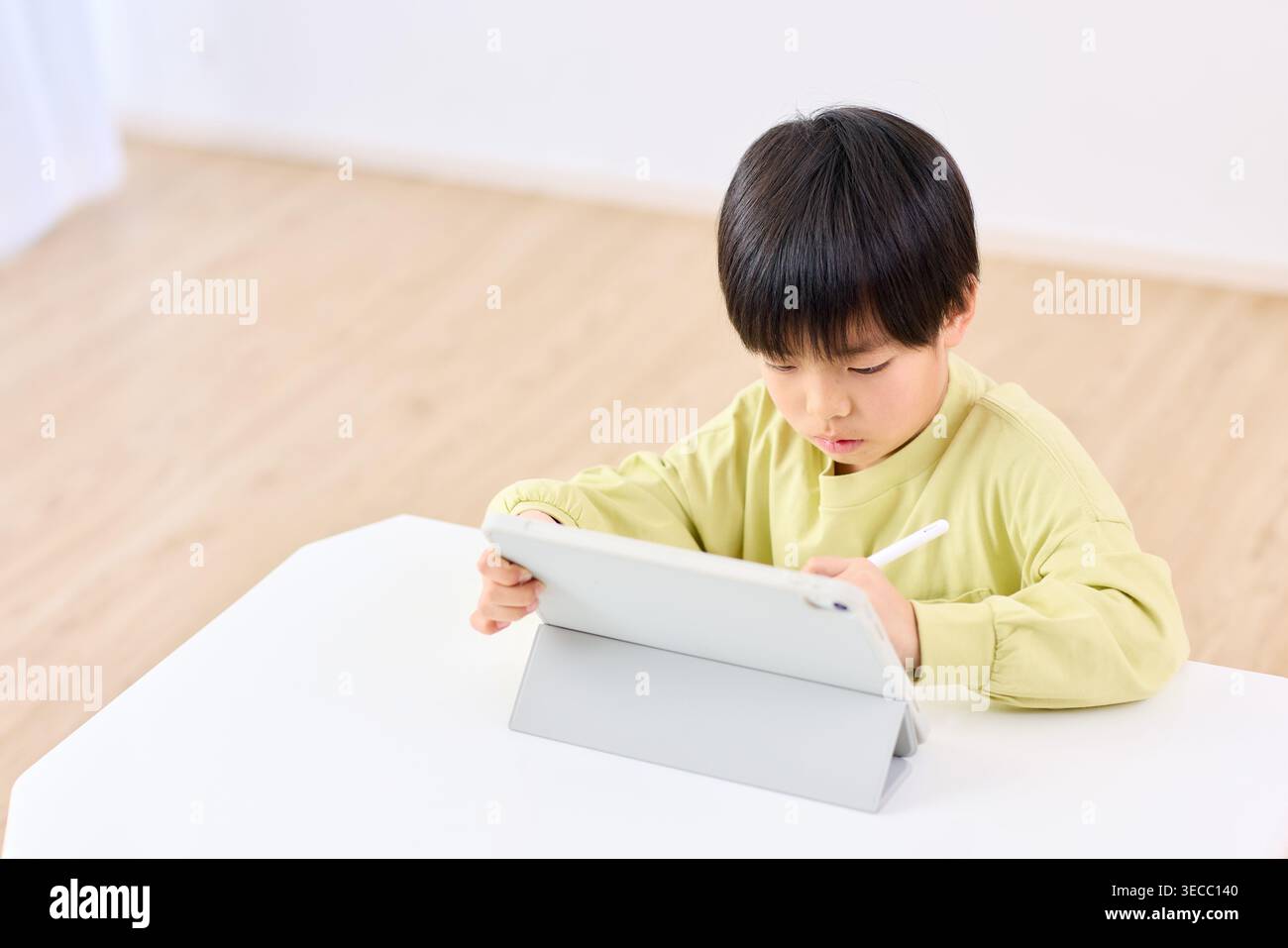 Japanese elementary school boy focused on tablet learning at home Stock Photo