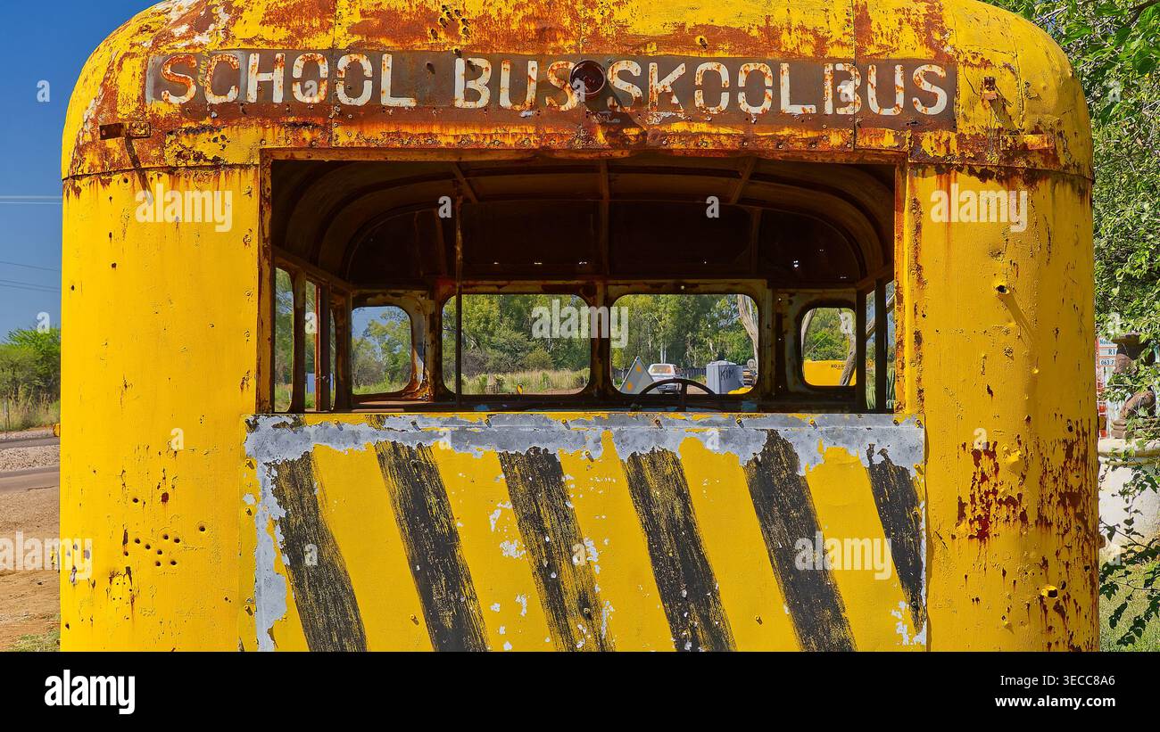 A rusting yellow and black striped skool bus with no windows sits ...