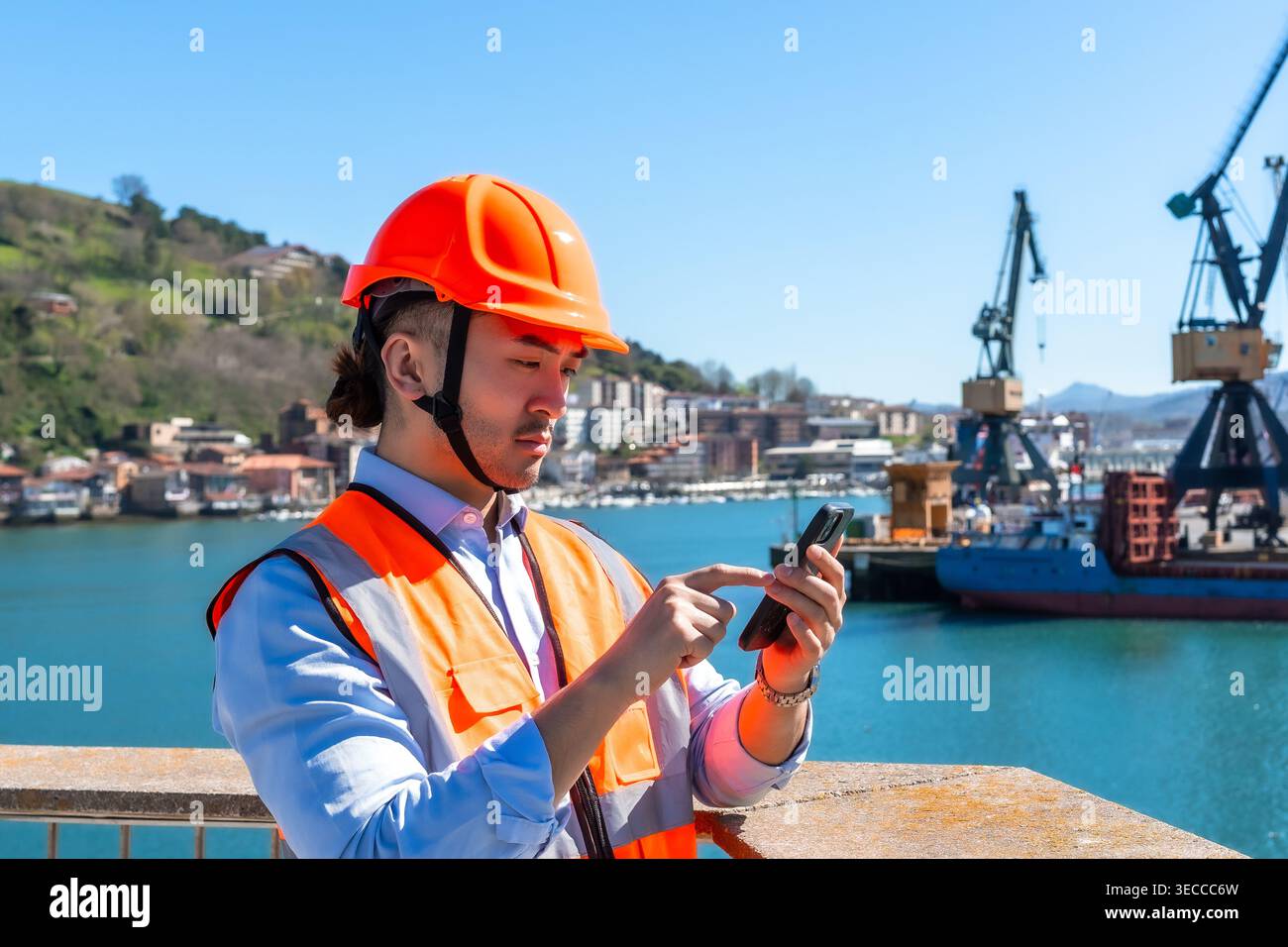 Asian port worker using smartphone checking logistics Stock Photo