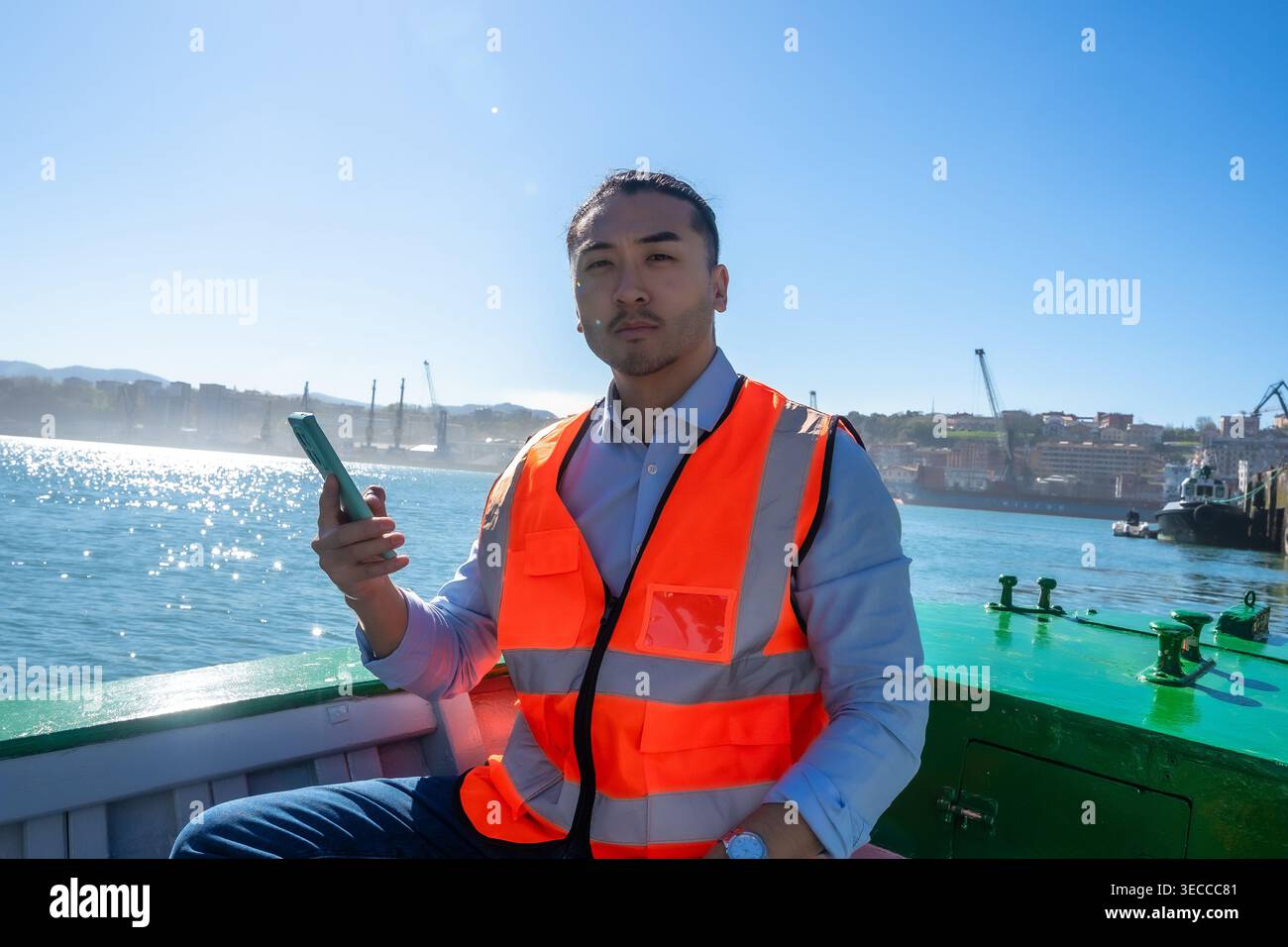 Cargo port worker using smartphone on boat Stock Photo