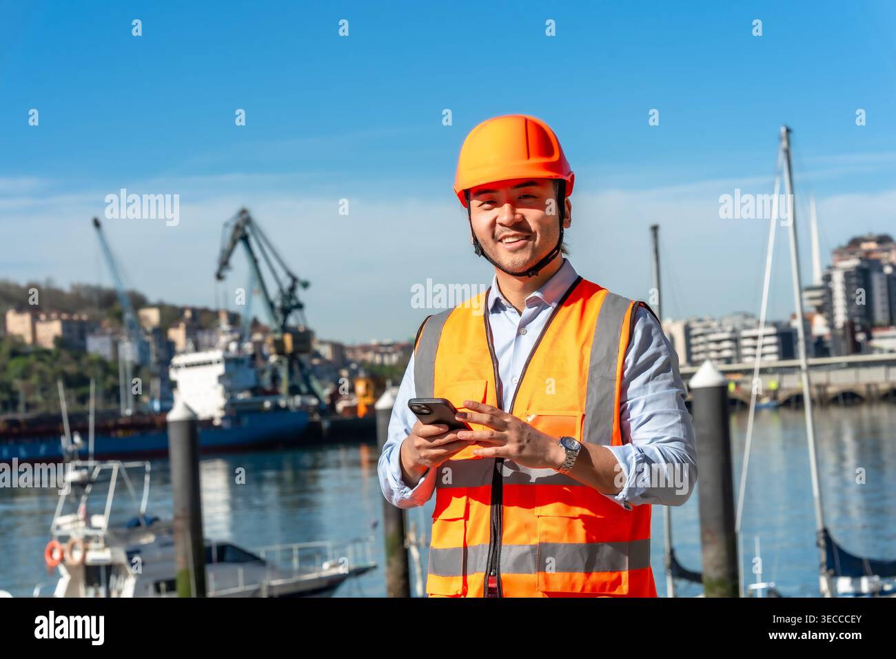 Young asian port worker using smartphone Stock Photo