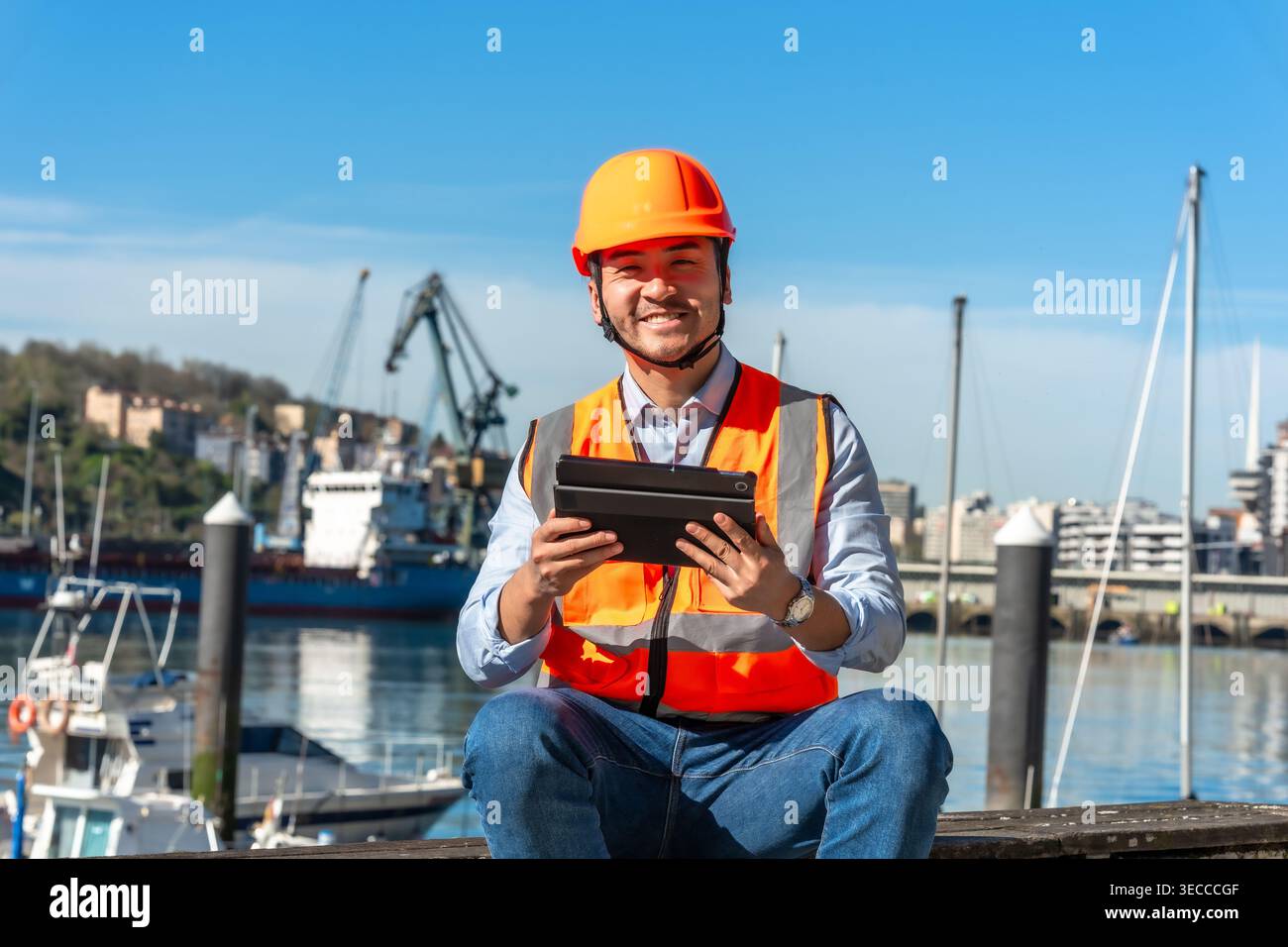 Worker in safety vest using tablet at port Stock Photo