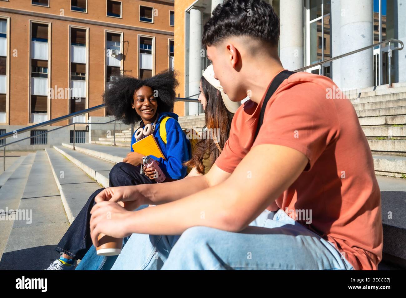 Diverse students talking and laughing on campus steps Stock Photo