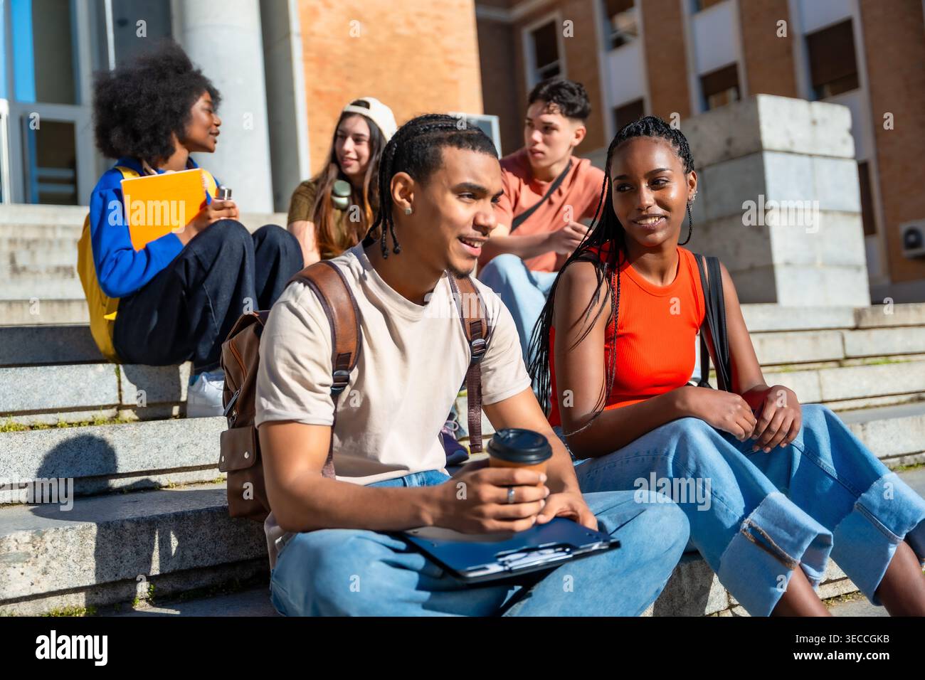 Diverse students sitting on campus steps talking Stock Photo