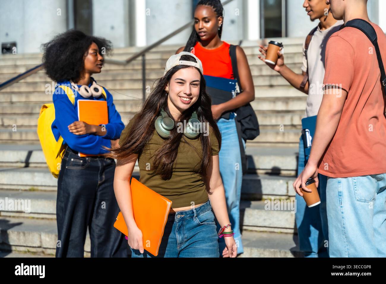 Diverse students walking, talking, and smiling on university campus Stock Photo