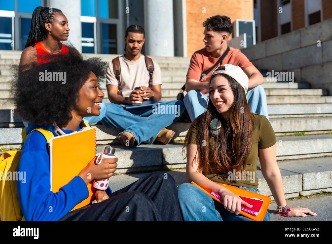 Diverse students relaxing together on university campus stairs Stock Photo