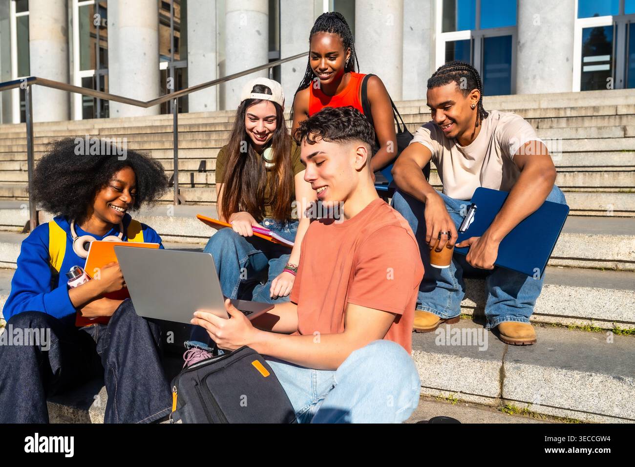 Multiethnic university students sitting on campus steps studying together Stock Photo