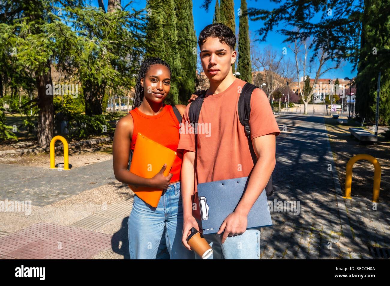 Diverse students carrying folders looking at camera on university campus Stock Photo