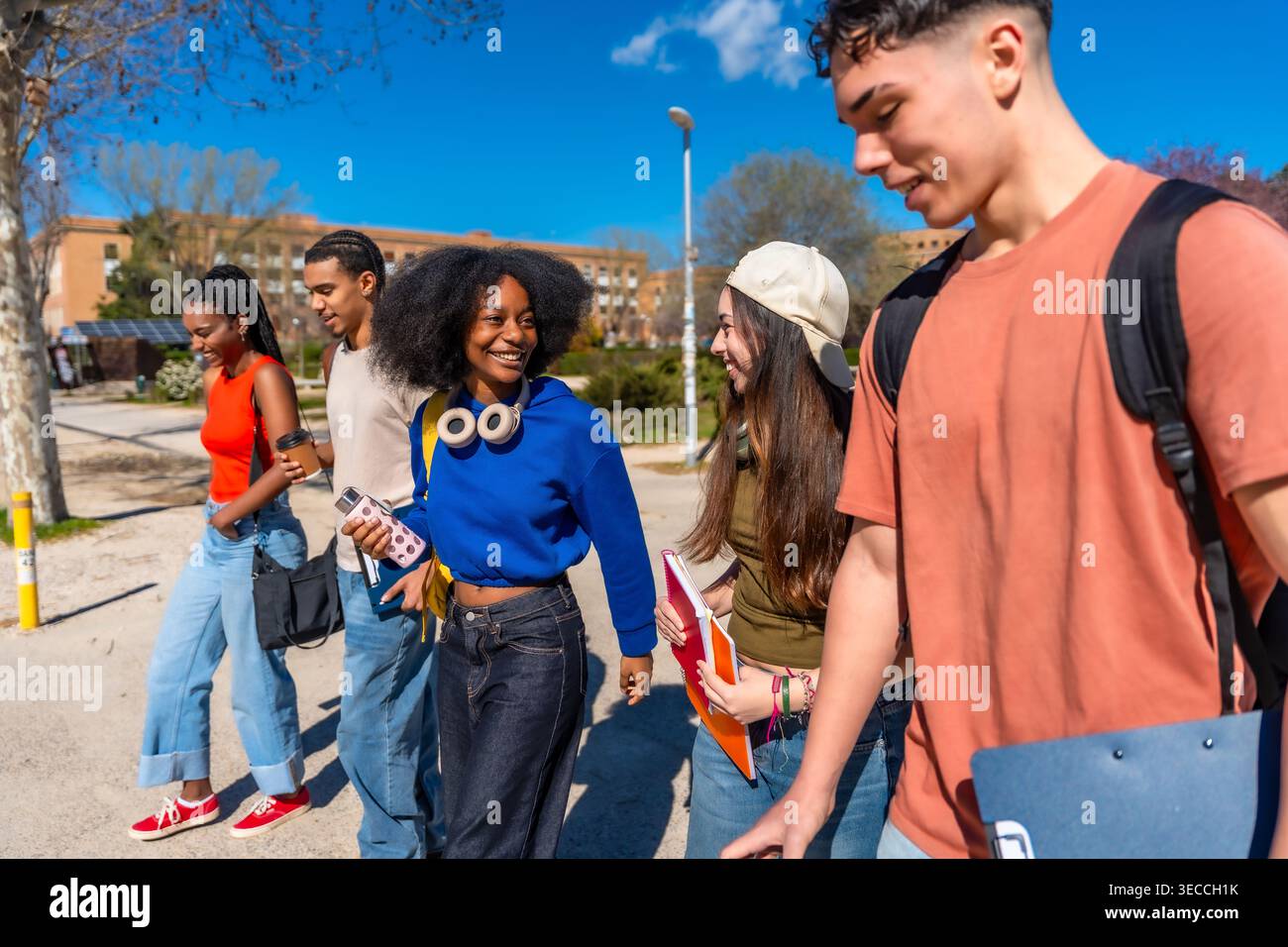 Diverse students walking, talking, and smiling on campus Stock Photo