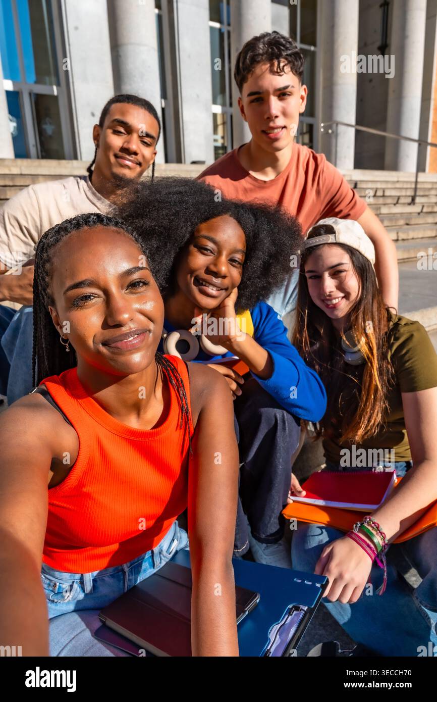 Diverse students taking selfie on university campus stairs Stock Photo