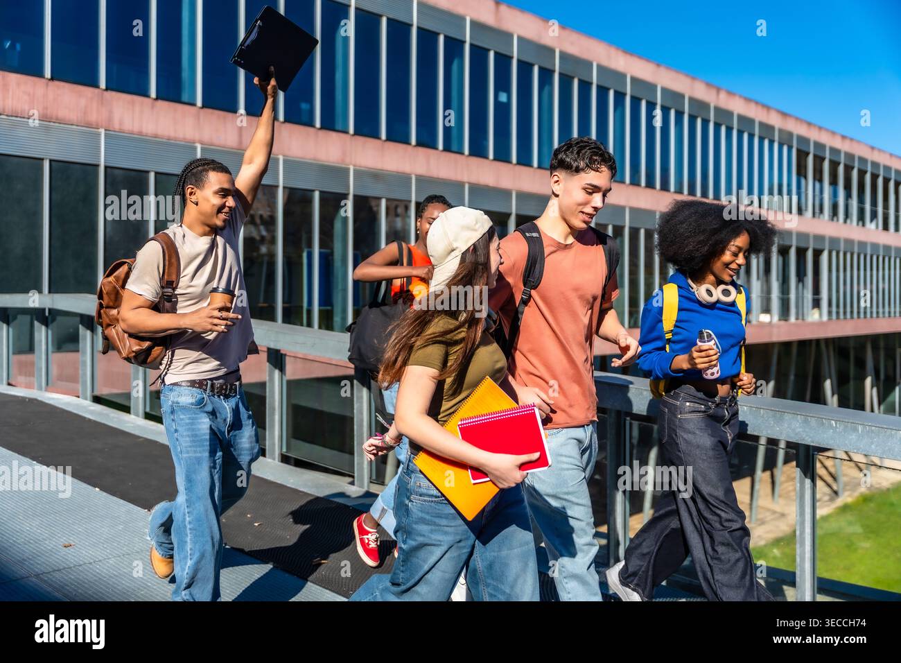 Diverse university students walking together on campus bridge Stock Photo
