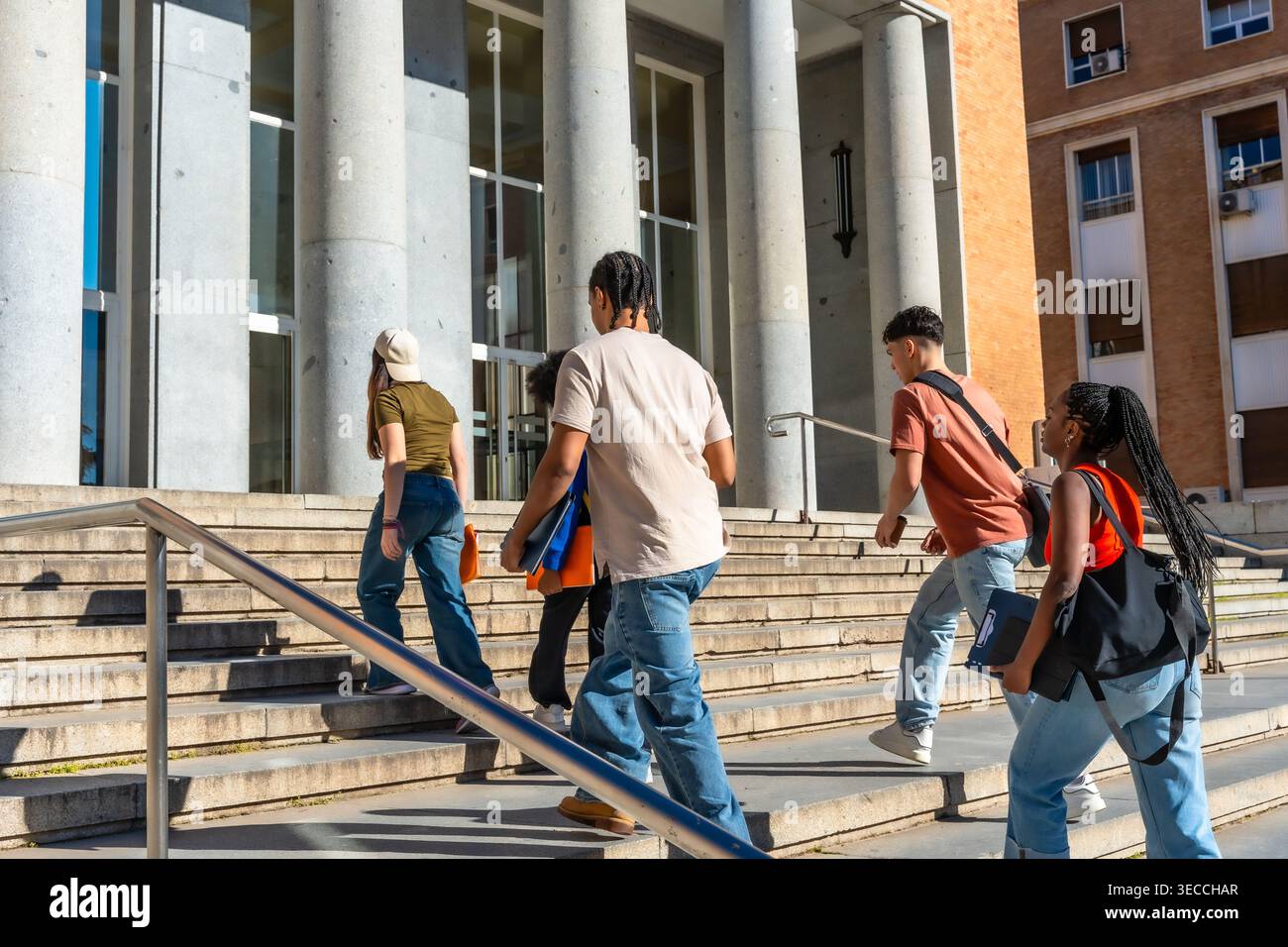Diverse students walking up stairs on university campus Stock Photo