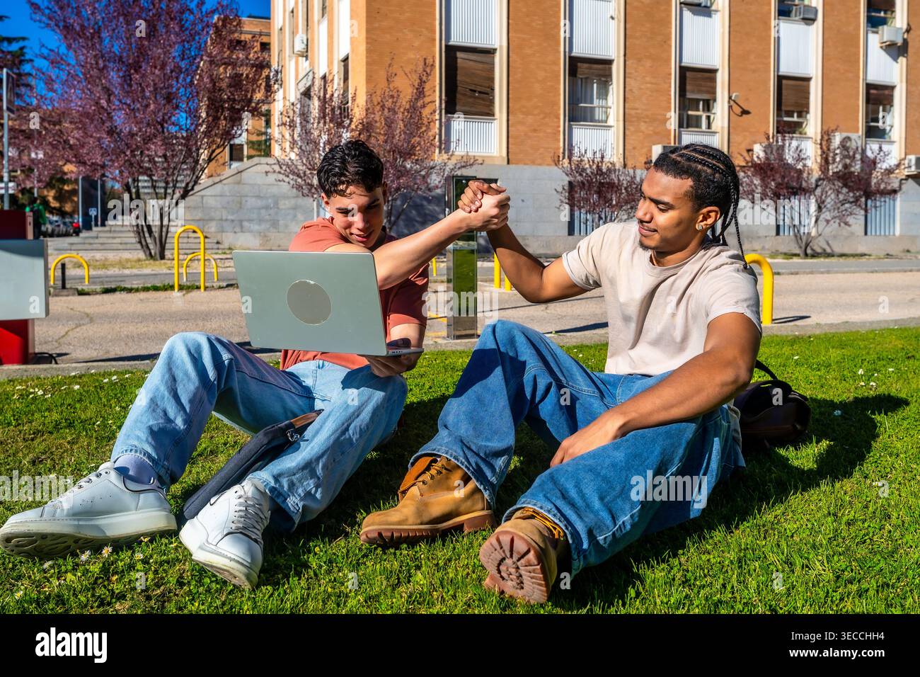 Diverse students collaborating on laptop at university campus Stock Photo