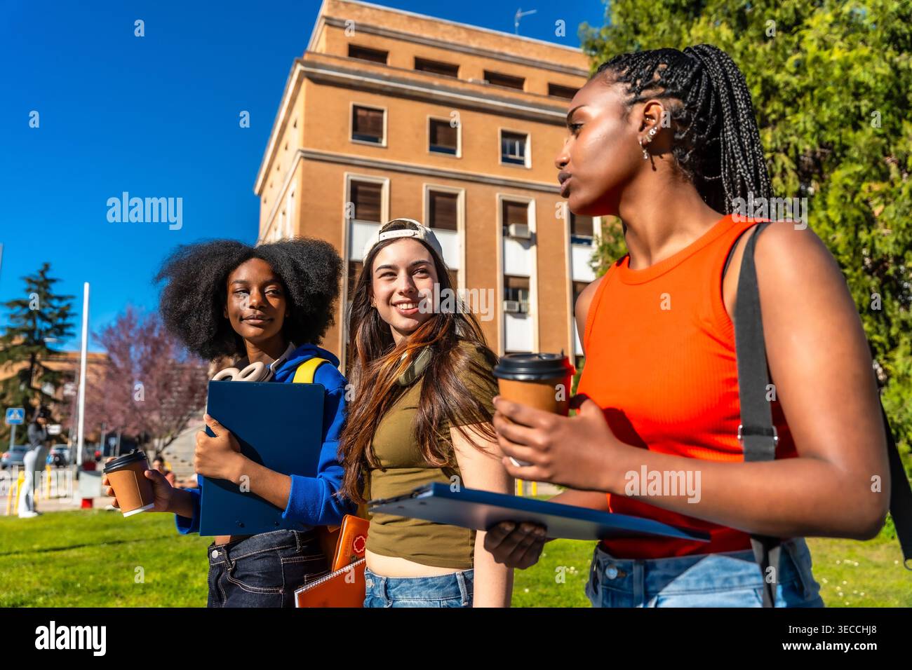 Diverse students walking on university campus discussing together Stock Photo
